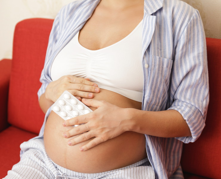 A pregnant woman holding pills